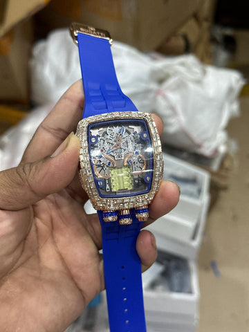 Premium luxury-style men’s watch with transparent skeleton dial, sparkling stone-studded case, and bold blue silicone strap. Perfect for party and fashion wear.